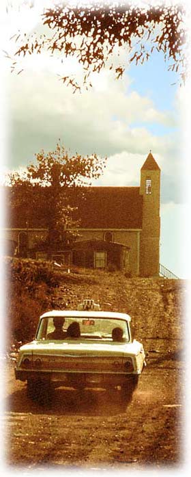 Car driving up the road by the church